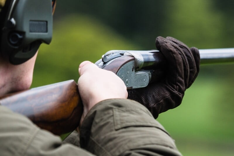 Image of a shotgun at a clay pigeon event with appropriate ear defence in frame